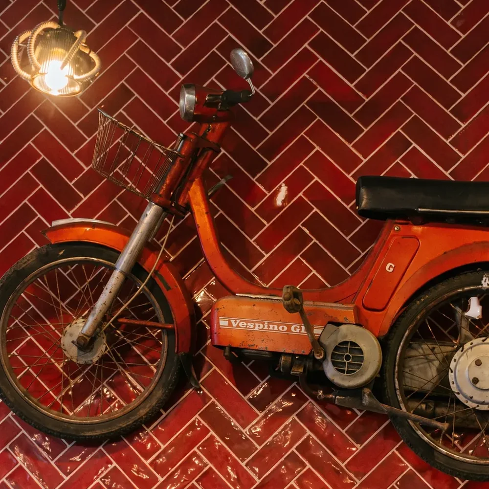 Rotes Moped an der Ziegelwand im Fischgrätmuster des Mi Locura, Mairena del Aljarafe